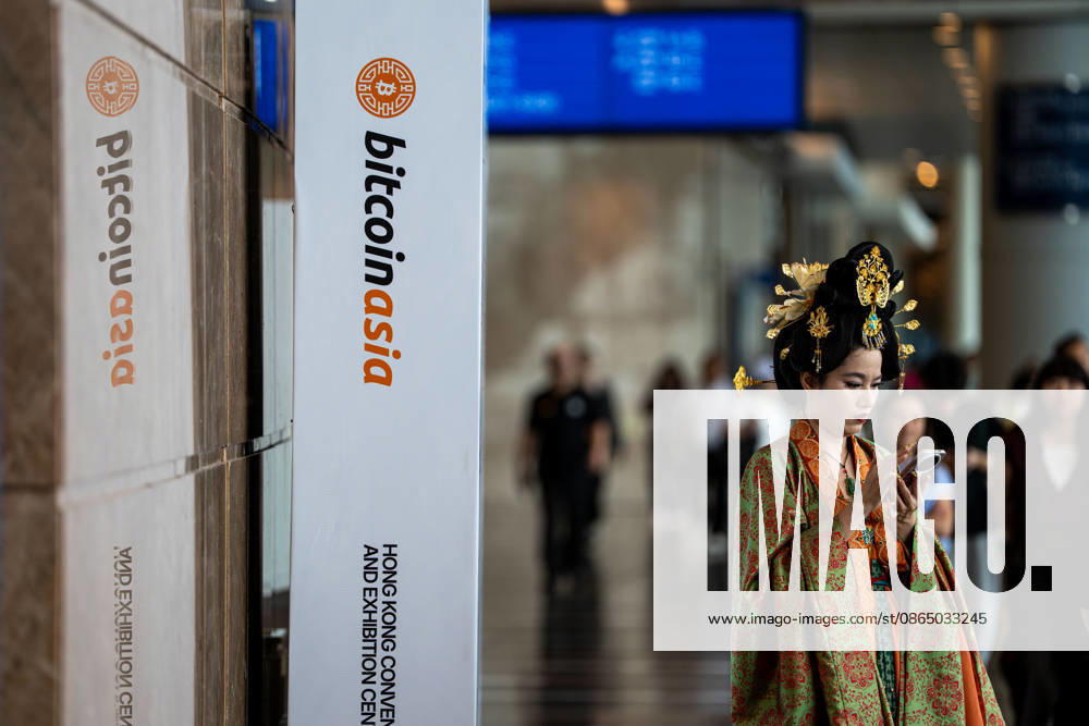 Bitcoin Asia Hong Kong 2026 A woman dress in a Chinese Hanfu looks at her phone next to a Bitcoin Asia logo at Bitcoin Asia 2026 on August 27, 2026 in Hong Kong. (Photo by Vernon Yuen Nexpher Images) HONG KONG