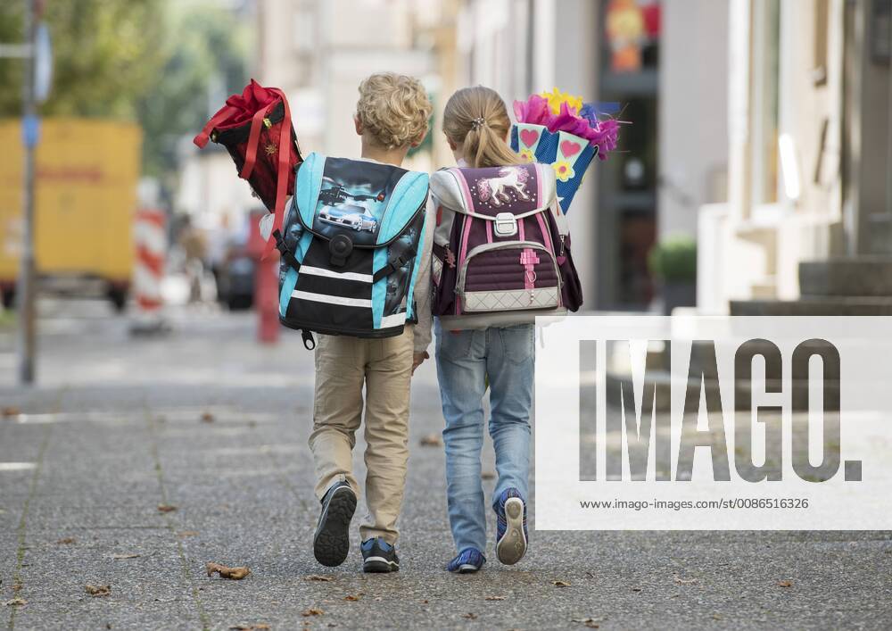 Two children with school bag on their way to school from behind model released