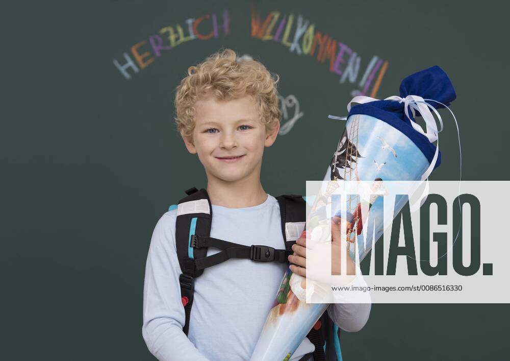Little boy stands with school bag in front of blackboard model released