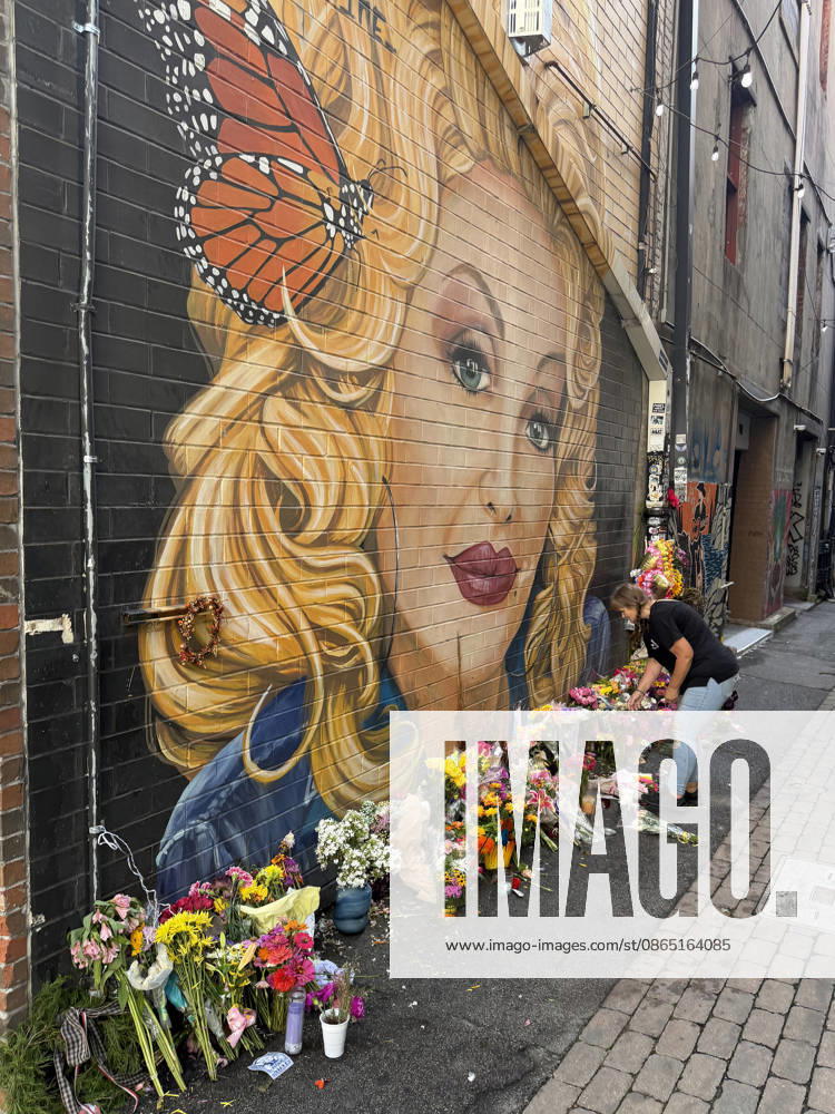 A woman arranges flowers at a memorial under a mural of Dolly Parton in Konxville, Tennessee on Friday, August 28, 2026. TEN20260828101 AARONxJOSEFCZYK
