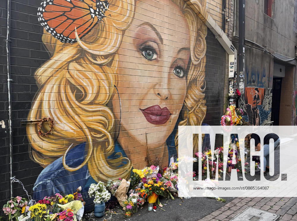 A woman arranges flowers at a memorial under a mural of Dolly Parton in Konxville, Tennessee on Friday, August 28, 2026. TEN20260828102 AARONxJOSEFCZYK