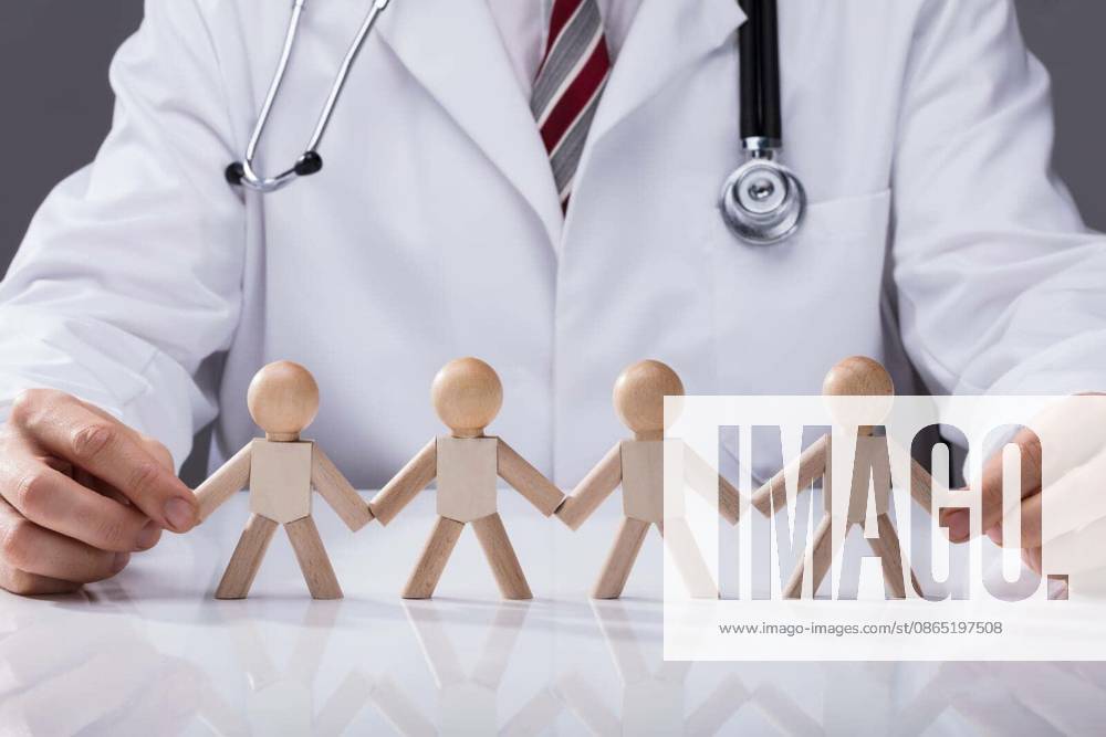 Close-up Of Doctor Holding Hand Of Wooden Figures Standing In A Row model released Symbolfoto
