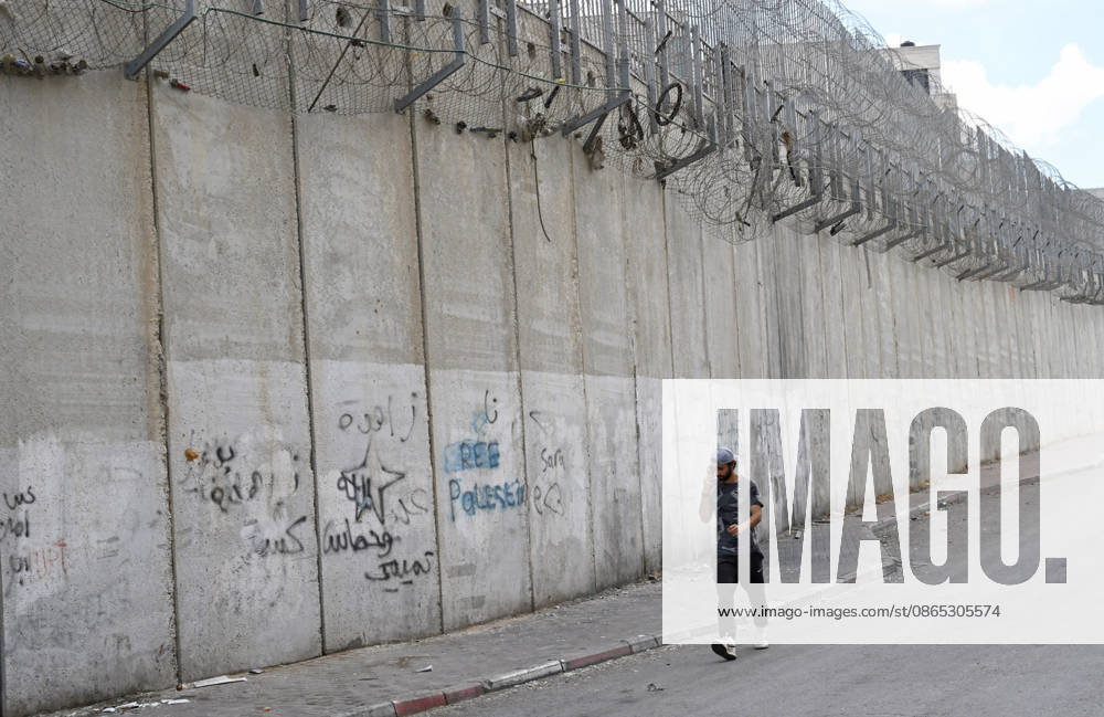 A Palestinian talks on a cellphone beside the Israeli separation wall that cuts through Beit Hanina in East Jerusalem on Sunday, August 30, 2026. Thousands of Palestinian residents of East Jerusalem are forced to go through time consuming checkpoints to reach their schools, jobs, hospitals and visit family because of the separation barrier. JER2026083006 DEBBIExHILL