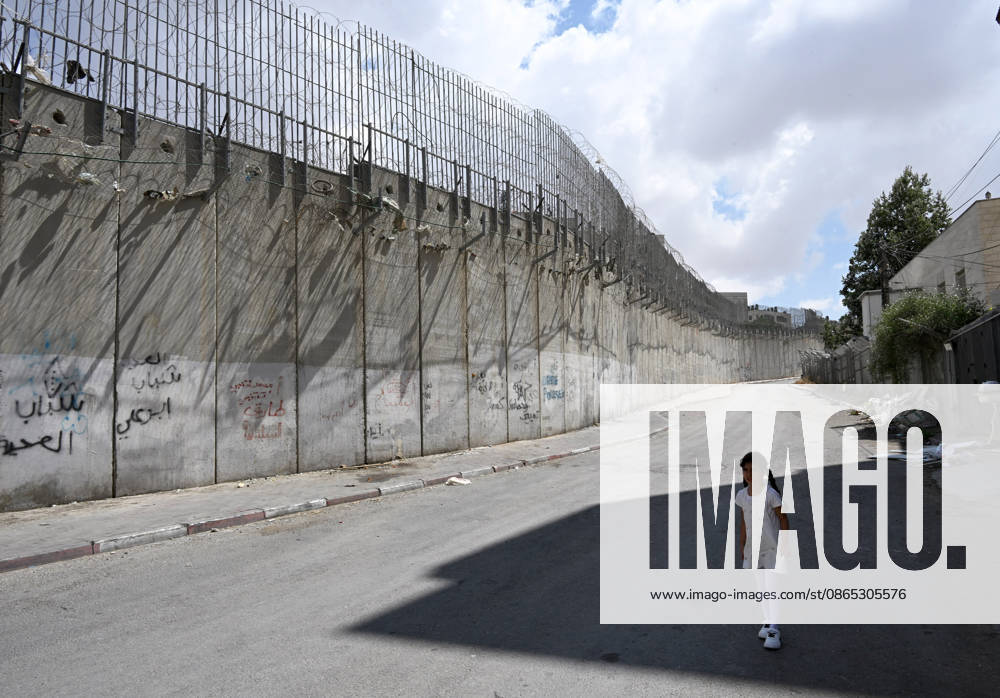 A Palestinian girl stands in the shade beside the Israeli separation wall that cuts through Beit Hanina in East Jerusalem on Sunday, August 30, 2026. Thousands of Palestinian residents of East Jerusalem are forced to go through time consuming checkpoints to reach their schools, jobs, hospitals and visit family because of the separation barrier. JER2026083007 DEBBIExHILL