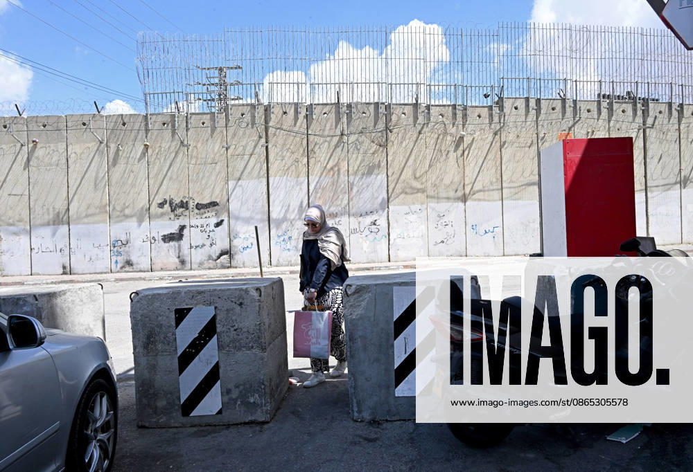 A Palestinian woman carries groceries through barriers near the Israeli separation wall that cuts through Beit Hanina in East Jerusalem on Sunday, August 30, 2026. Thousands of Palestinian residents of East Jerusalem are forced to go through time consuming checkpoints to reach their schools, jobs, hospitals and visit family because of the separation barrier. JER2026083008 DEBBIExHILL