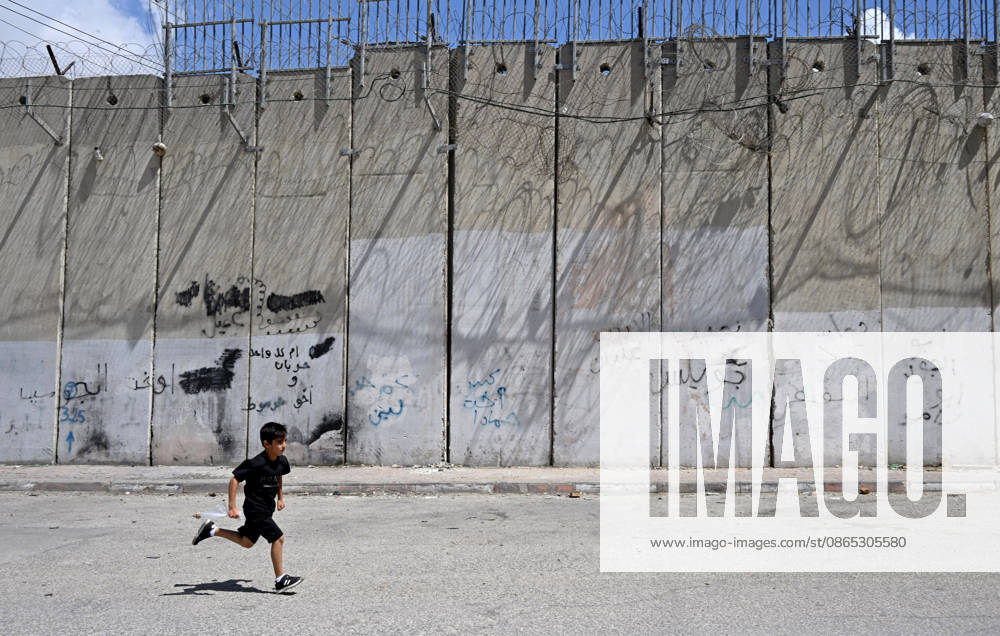 A Palestinian boy runs beside the Israeli separation wall that cuts through Beit Hanina in East Jerusalem on Sunday, August 30, 2026. Thousands of Palestinian residents of East Jerusalem are forced to go through time consuming checkpoints to reach their schools, jobs, hospitals and visit family because of the separation barrier. JER2026083009 DEBBIExHILL