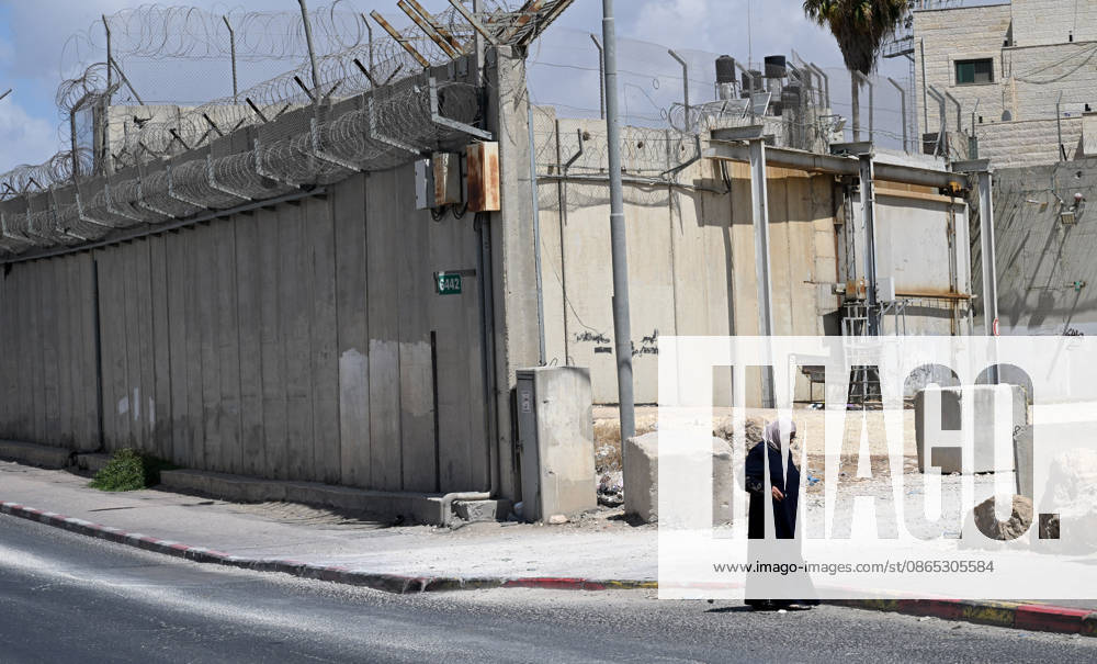 A Palestinian woman stands near the Israeli separation wall that cuts through Beit Hanina in East Jerusalem on Sunday, August 30, 2026. Thousands of Palestinian residents of East Jerusalem are forced to go through time consuming checkpoints to reach their schools, jobs, hospitals and visit family because of the separation barrier. JER2026083012 DEBBIExHILL