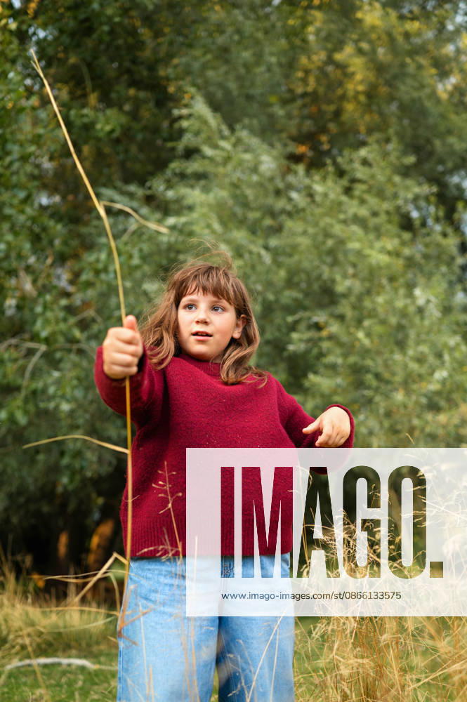 Young girl exploring nature while holding a long grass stem Kettering, England, United Kingdom CR_JNDO260826-2112884-01 ,model released, Symbolfoto ,property released