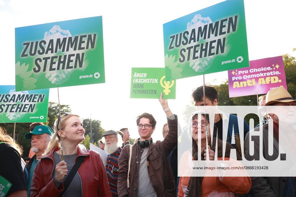 Supporters of the Alliance 90 The Greens party hold signs at the start of a rally with the slogan Time to Act, Stop the AfD in front of the Brandenburg Gate, Platz des 18. März, in Berlin
