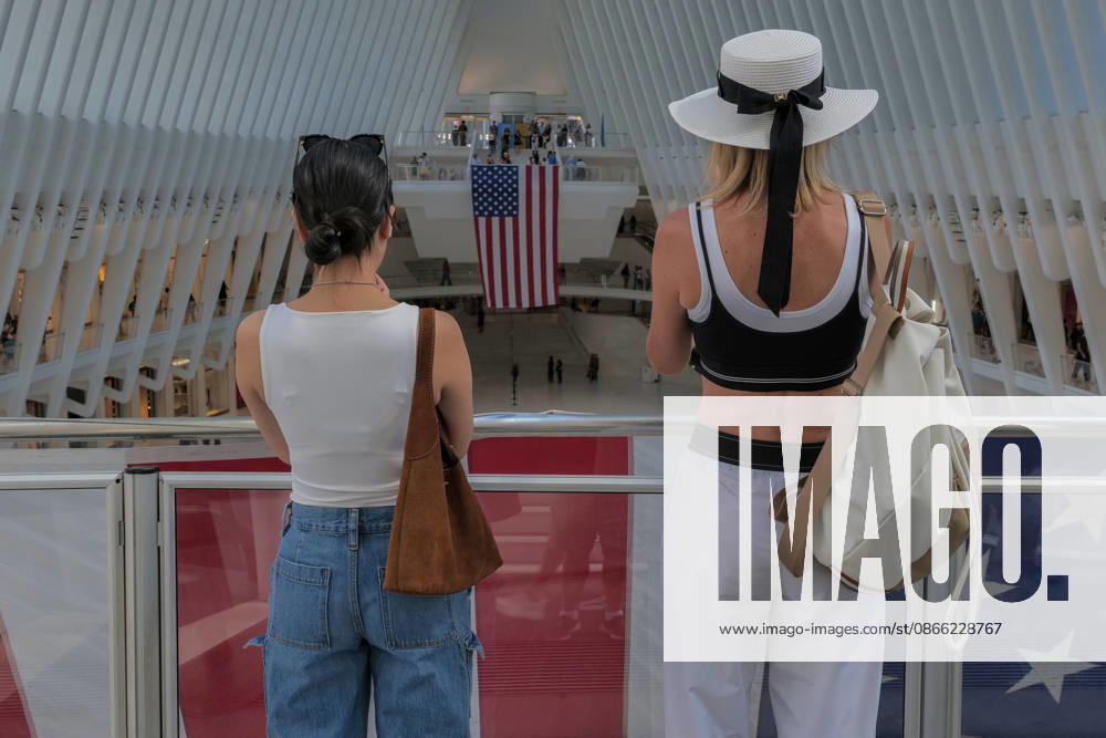 Visitors take photos of the large US Flag at the Oculus across from the 9 11 Memorial and museum..The Spanish architect Santiago Calatrava designed architectural landmark that functions as a major transportation hub.and upscale shopping destination. The vast light filled interior features a massive overhead skylight creating a cathedral.like atmosphere, the outside resembles a bird being released from a child s hands symbolizing resilience and rebirth .at the World Trade Center site. New York USA - ZUMAh156 20260907_znp_h156_005