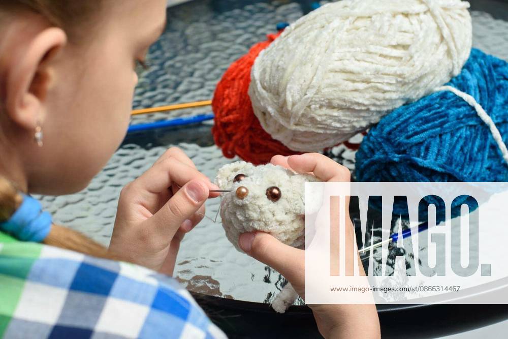 Girl sews on the eyes of a homemade soft toy mouse model released Symbolfoto