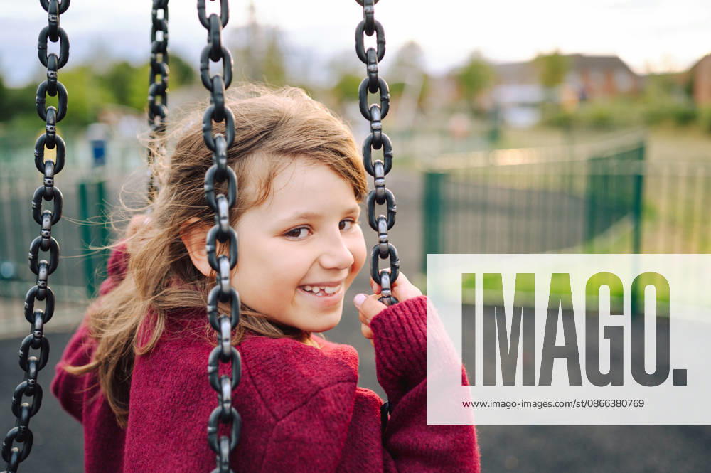 Happy young girl smiling while on a playground swing set Corby, England, United Kingdom CR_JNDO260908B7-2120816-01 ,model released, Symbolfoto ,property released