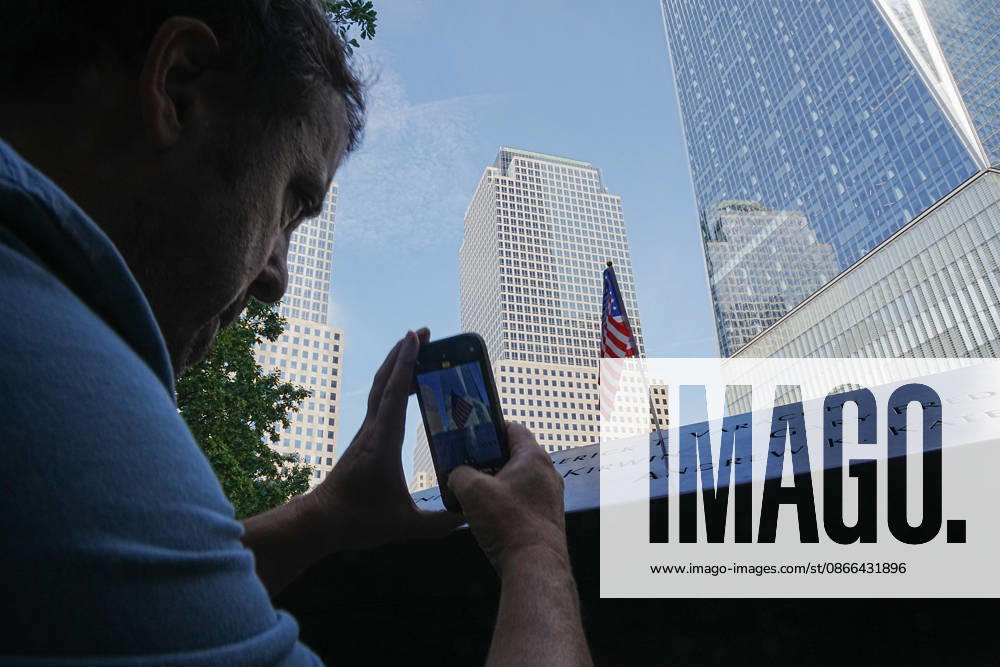 Visitors take a photo of an American flag at the North Tower reflecting pool with One World Trade Center in the background ahead of the 25th anniversary of the attacks of September 11 at the 9 11 Memorial on September 9, 2026 in New York. New York USA - ZUMAb148 20260909_zap_b148_053