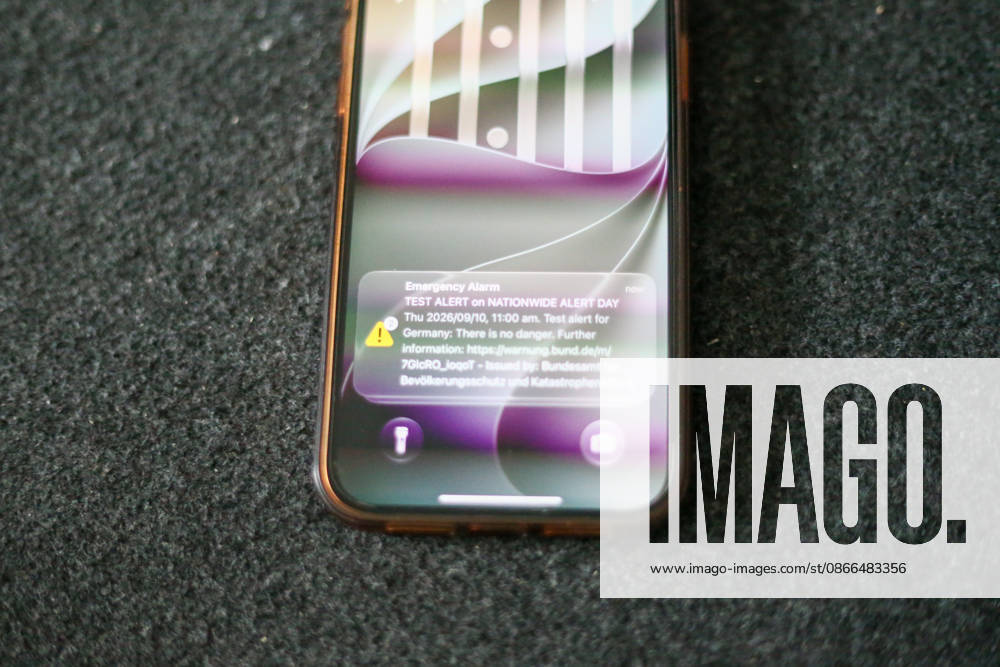Germany, Europe: A smartphone lies on a dark surface, displaying a test alert on its lock screen for the nationwide Warning Day. The cell broadcast alert from the Federal Office for Civil Protection and Disaster Assistance (BBK) is visible on the screen. Stock image related to emergency warning systems, civil protection, crisis preparednes