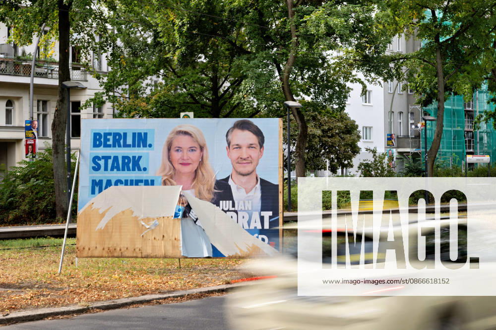 Berlin, September 11, 2026: A damaged, partially torn campaign poster with the slogan Make Berlin Strong stands by the roadside in Berlin; in the foreground, a car drives by. A torn campaign poster for the Berlin election by the roadside.
