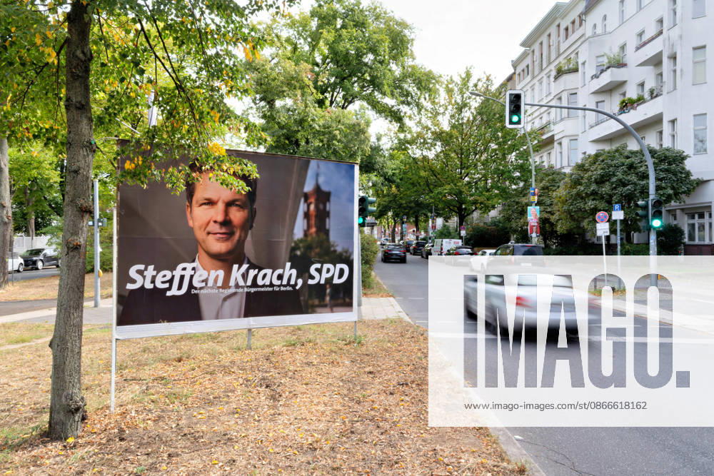An election poster featuring Steffen Krach (SPD) stands on a street in Berlin, with traffic and residential buildings in the background. SPD election poster for Steffen Krach on a busy street in Berlin