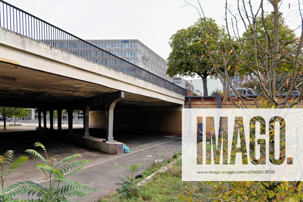 A view from under a bridge of a modern office building in Berlin; the retaining wall is clad in yellow and red bricks. Underpass and new building in Berlin