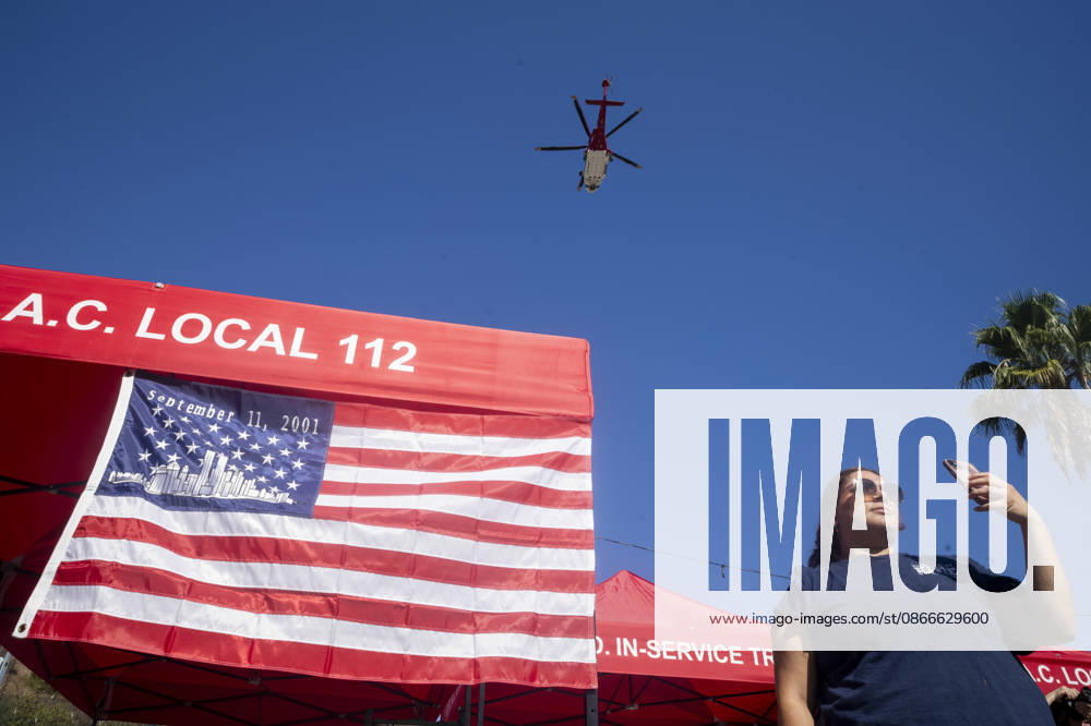 A woman takes photos next to a 9 11 remembrance flag during a helicopter flyover as the Los Angeles Fire Department marks the 25th anniversary of the terrorist attacks at the Frank Hotchkin Memorial Training Center in Los Angeles, California, on Sept. 11, 2026. Los Angeles USA - ZUMAc68_ 20260911_zaf_c68_004