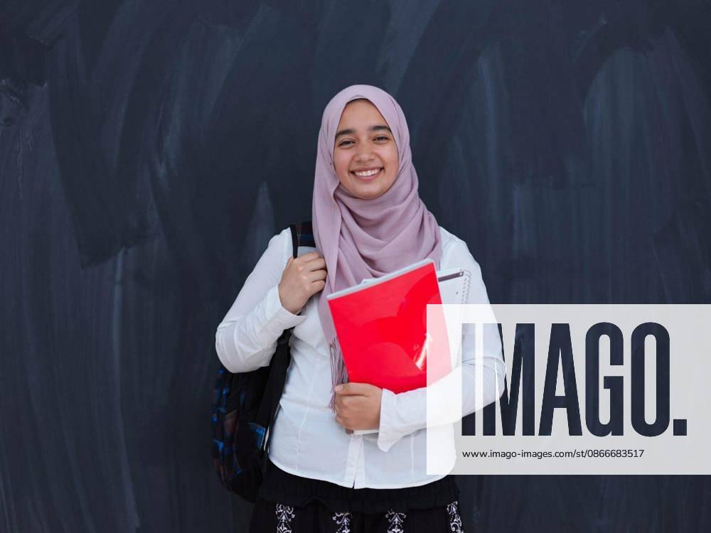 Portrait of happy female middle eastern university student against black chalkboard in classroom model released Symbolfoto