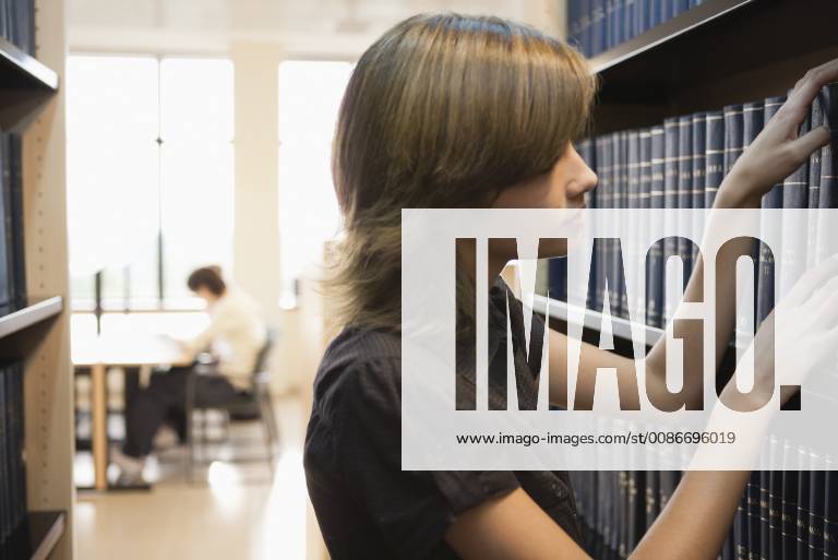 Young woman looking at books in library