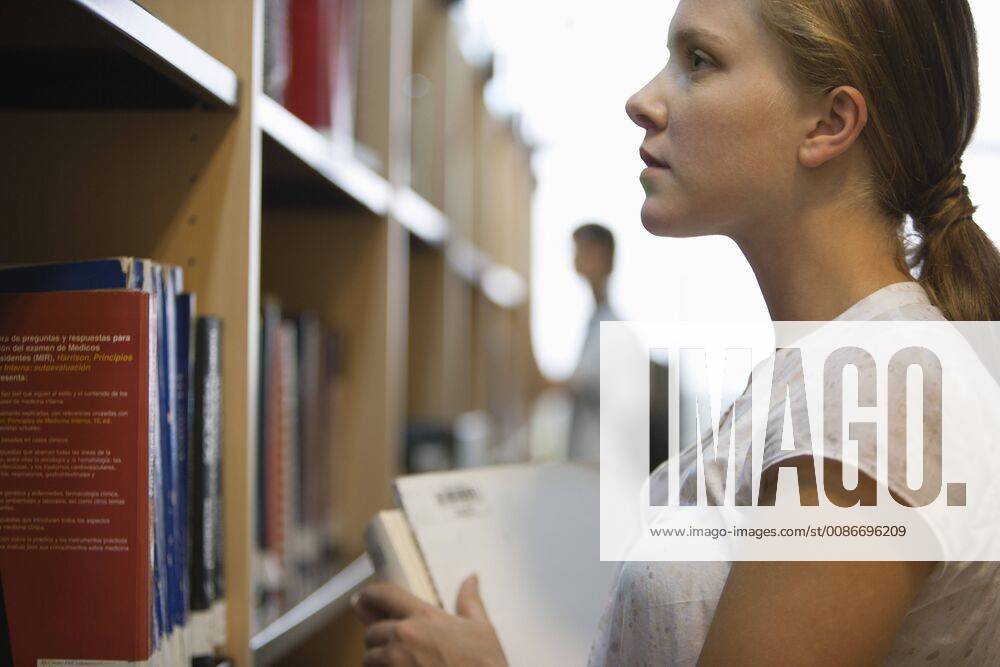 Young woman looking at books in library