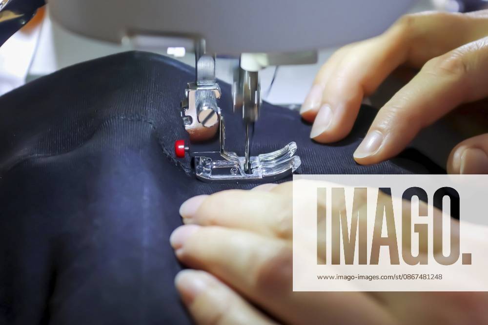 Nähkonzept. Weibliche Hände arbeiten an einer modernen Nähmaschine mit einigen Stoffen und Textilien Sewing concept. Female hands working at a modern sewing machine with some fabrics and textiles