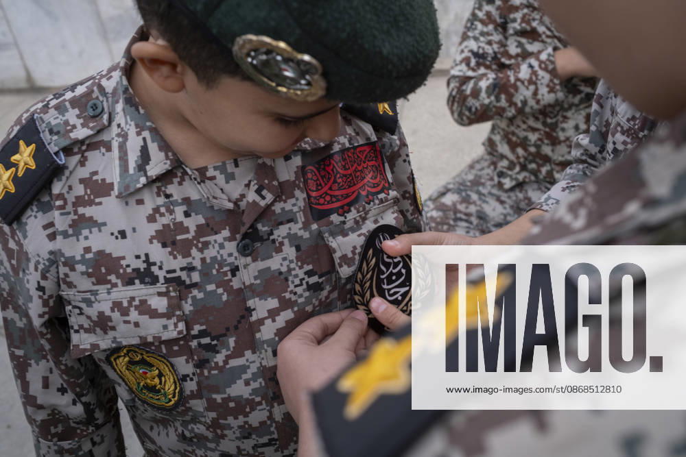 Opening Ceremony Of Second City-Square Military Training Camp An Iranian schoolboy wearing an Iranian Army military uniform helps his friend attach a badge for self-sacrificing forces as they prepare to take part in the opening ceremony of the second city-square military training camp in downtown Tehran, Iran, on October 3, 2026. The second City-Square Military Training Camp for the self-sacrificing forces was established by the Basij paramilitary force, with personnel from the Islamic Republic of Iran Army responsible for training the volunteers. Tehran Tehran Iran