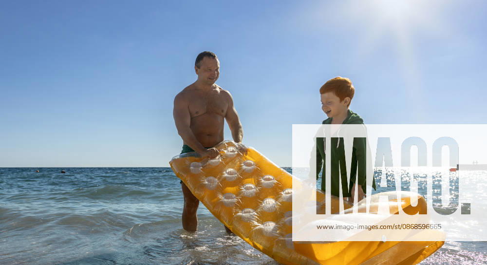 Father and son carry a yellow mattress into the sea model released, Symbolfoto, MBLF01424