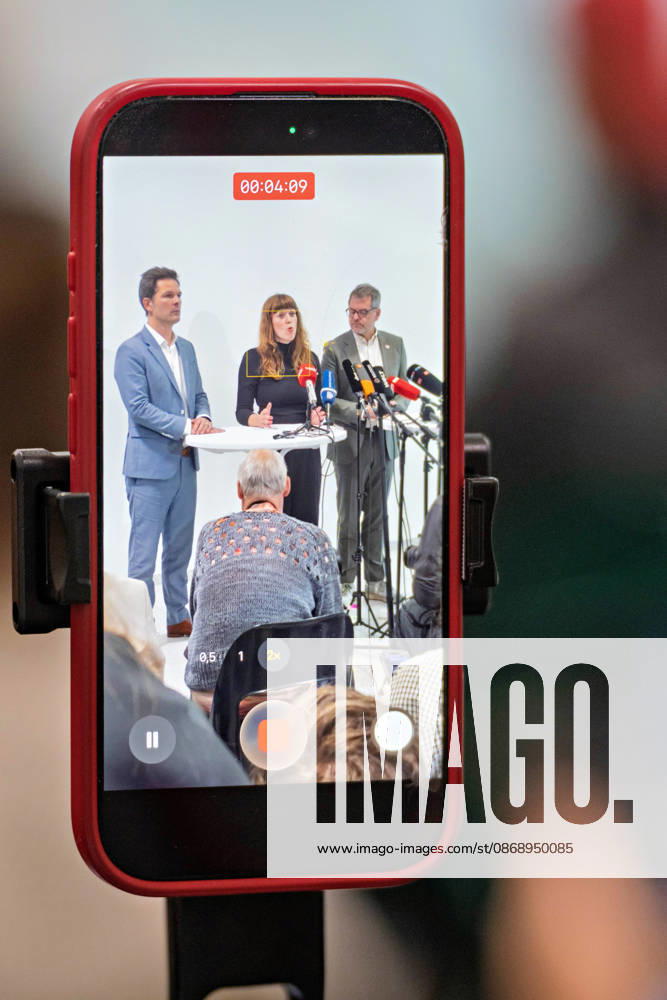 Berlin, October 8, 2026: Steffen Krach (SPD, left), Kerstin Wolter Ehling (Die Linke, M, and Werner Graf of Alliance 90 The Greens (right) can be seen on a smartphone screen during a joint press statement following the conclusion of their parties’ preliminary talks in the foyer of the Haus der Statistik. Press statement by The Left, The Greens, and the SPD in Berlin