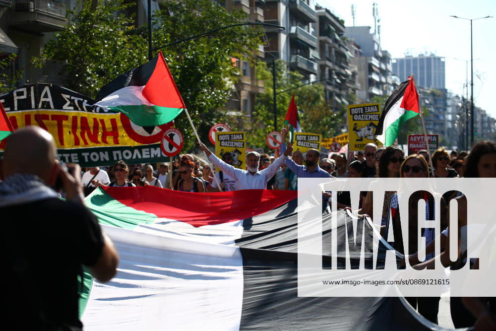 Demonstrators carry a large Palestinian flag during a pro-Palestinian march, with a protester raising both arms in the background. Athens GREECE - ZUMAx103 20261010_zip_x103_021