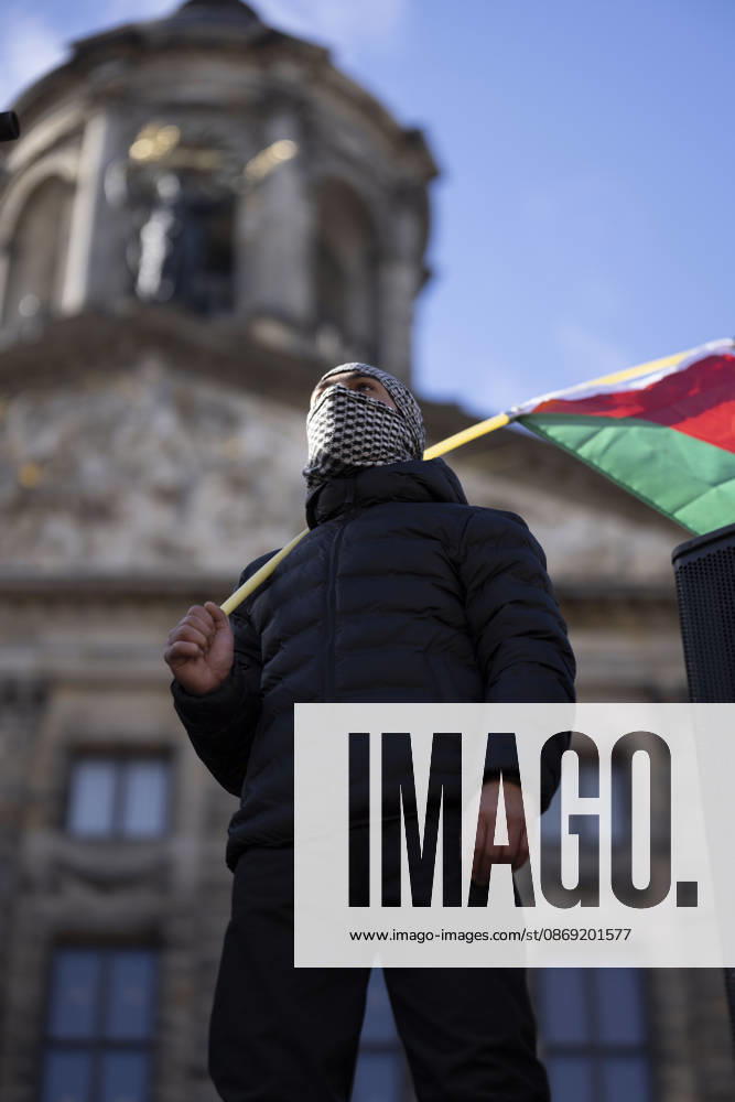 Amsterdam, Noord-Holland, The Netherlands: October 11, 2026, Amsterdam, Netherlands: A demonstrator with a keffiyeh covering their face holds a Palestinian flag outside the Royal Palace during a pro-Palestinian protest at Dam Square. Amsterdam The Netherlands - ZUMAl165 20261011_zip_l165_001