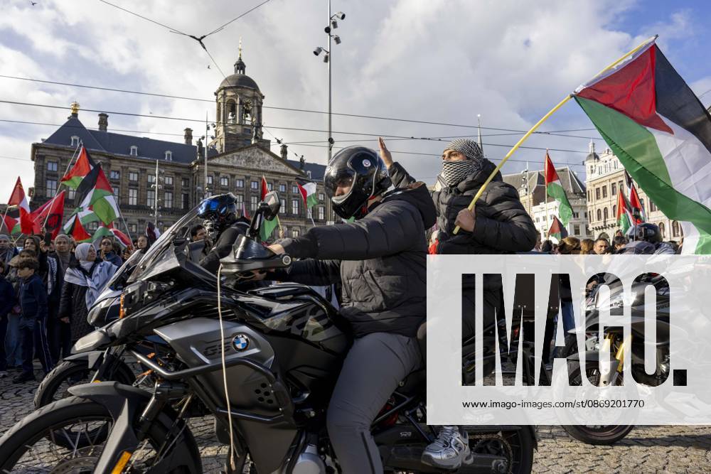 Amsterdam, Noord-Holland, The Netherlands: October 11, 2026, Amsterdam, Netherlands: A motorcycle passenger holds a Palestinian flag and raises one hand during a pro-Palestinian protest at Dam Square, with the Royal Palace of Amsterdam in the background. Amsterdam The Netherlands - ZUMAl165 20261011_zip_l165_015