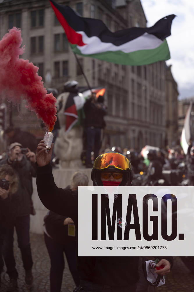 Amsterdam, Noord-Holland, The Netherlands: October 11, 2026, Amsterdam, Netherlands: A demonstrator wearing a motorcycle helmet holds a canister emitting red smoke during a pro-Palestinian protest at Dam Square. Amsterdam The Netherlands - ZUMAl165 20261011_zip_l165_018
