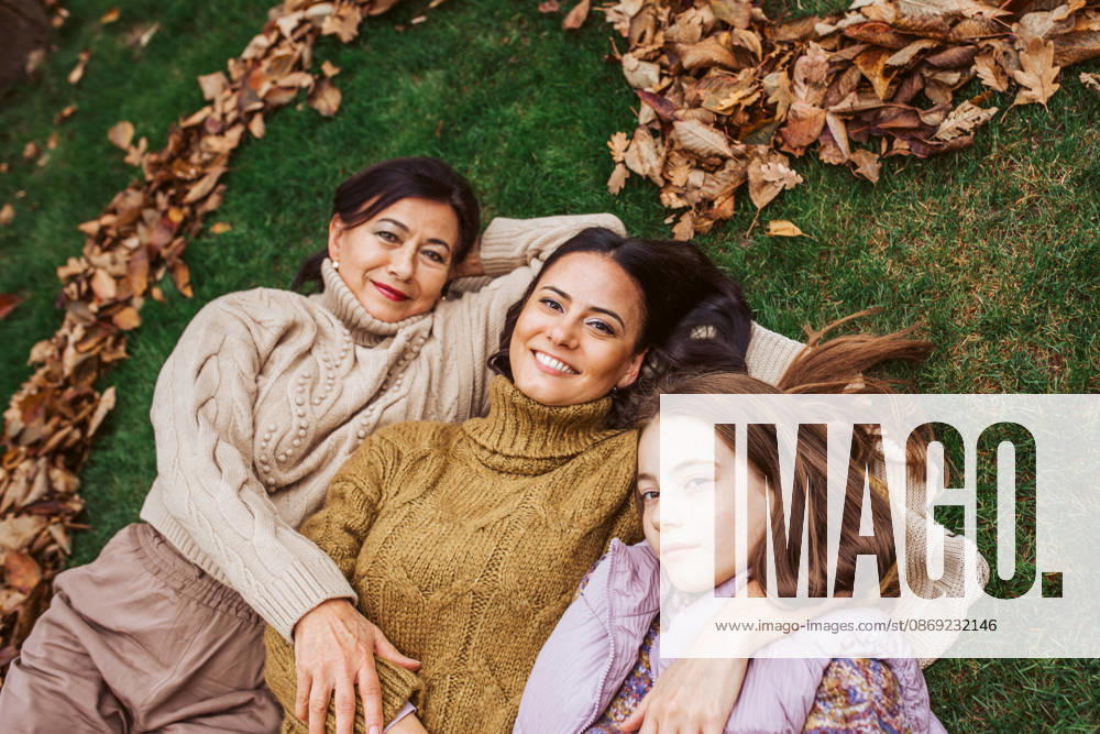 Mother, grandmother and daughter, laying on grass in the middle of heart from leaves. Portrait of mother, grandmother and daughter, laying on grass in the middle of heart from leaves. model released