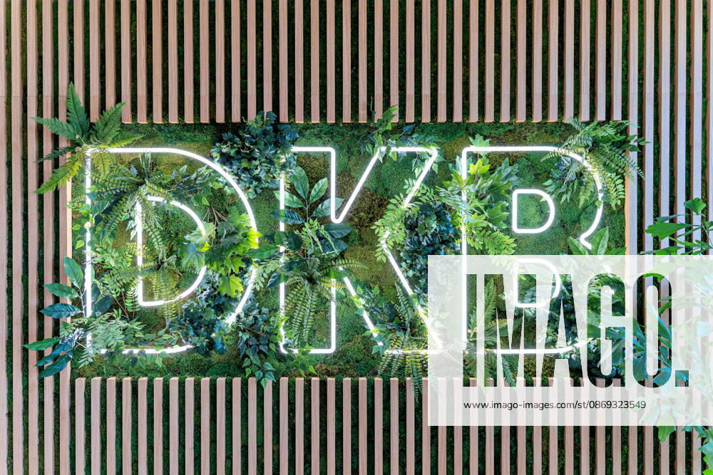 Berlin, 13.10.2026: Das DKB-Logo als Leuchtschrift in einer Pflanzenwand mit Moos und Holzlamellen im neuen DKB-Campus in der Europacity in Berlin-Mitte. Die Deutsche Kreditbank AG (DKB) hat ihren neuen Hauptsitz heute offiziell eröffnet. Der von Kleihues + Kleihues entworfene, rund 82 Meter hohe Komplex besteht aus drei Gebäudeteilen mit fünf, elf und 19 Geschossen und rund 35.000 Quadratmetern Mietfläche; entwickelt wurde er von der CA Immo unter dem Projektnamen Upbeat. Rund 2.600 Mitarbeitende des DKB-Konzerns, die bislang auf mehrere Berliner Standorte verteilt waren, arbeiten nun gemeinsam im Campus. Die DKB ist Exklusivmieterin und hat einen Mietvertrag über 15 Jahre abgeschlossen. Zum Campus gehören neben modernen Arbeit