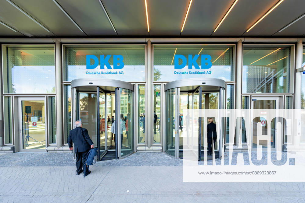 Berlin, 13.10.2026: Besucher gehen durch die Drehtüren am Eingang des neuen DKB-Campus in der Europacity in Berlin-Mitte, darüber der Schriftzug DKB Deutsche Kreditbank AG. Die Deutsche Kreditbank AG (DKB) hat ihren neuen Hauptsitz heute offiziell eröffnet. Der von Kleihues + Kleihues entworfene, rund 82 Meter hohe Komplex besteht aus drei Gebäudeteilen mit fünf, elf und 19 Geschossen und rund 35.000 Quadratmetern Mietfläche; entwickelt wurde er von der CA Immo unter dem Projektnamen Upbeat. Rund 2.600 Mitarbeitende des DKB-Konzerns, die bislang auf mehrere Berliner Standorte verteilt waren, arbeiten nun gemeinsam im Campus. Die DKB ist Exklusivmieterin und hat einen Mietvertrag über 15 Jahre abgeschlossen. DKB eröffnet
