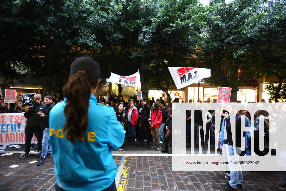 A police officer stands in the foreground as university students march carrying flags and placards demanding lower education costs and improved student welfare. Athens GREECE - ZUMAx103 20261013_zip_x103_010