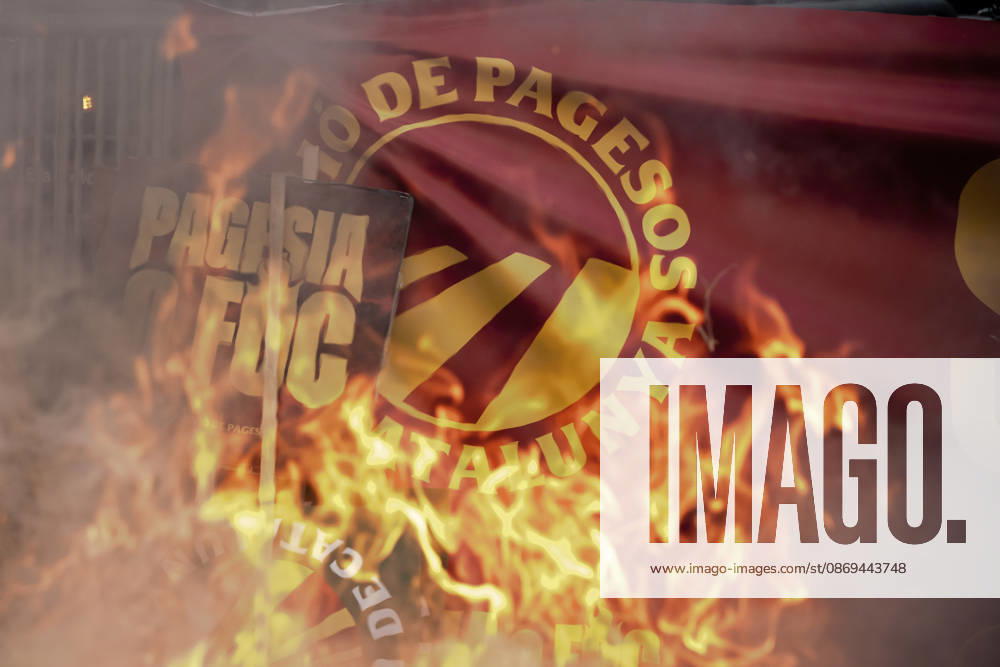 A sign reading Pagesia o foc ( Farming or Fire ) is seen through flames outside the Catalan Agriculture Ministry during a farmers protest in Barcelona demanding fair prices, lower fuel costs and protection against unfair competition from imports. Barcelona Spain - ZUMAo105 20261014_fap_o105_011