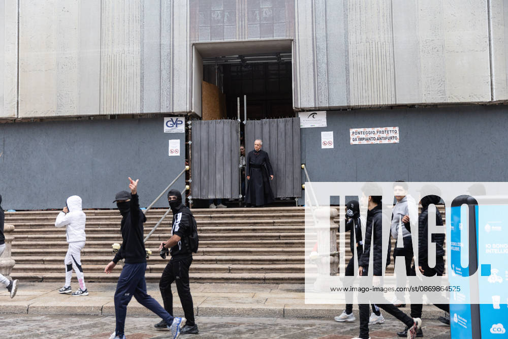 IPA89867615 - Milan, October 18, 2026: More Clashes and Looting in Downtown Milan the Day After the Protest; pictured: a priest closes the church to protesters seeking shelter