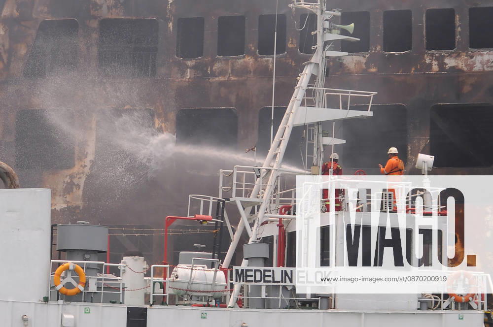 Efforts are underway to extinguish a fire that broke out on a passenger ferry in Indonesia s Cilegon PELABUHAN MERAK, CILEGON, INDONESIA - OCTOBER 21: Fireboats take turns spraying water onto the passenger ferry KMP Batumandi to cool down the vessel after it caught fire while preparing to dock off Merak Port in Cilegon, Banten, Indonesia on Wednesday, October 21, 2026. The vessel caught fire on Tuesday, October 20, and rescue operations remain underway as the ship continues to emit smoke. Water is continuously sprayed to cool the vehicle deck containing numerous cars, motorcycles, buses, and trucks, while authorities confirm no fatalities have been reported. Dasril Roszandi Anadolu Pelabuhan Merak Indonesia. Editorial use only. Please get