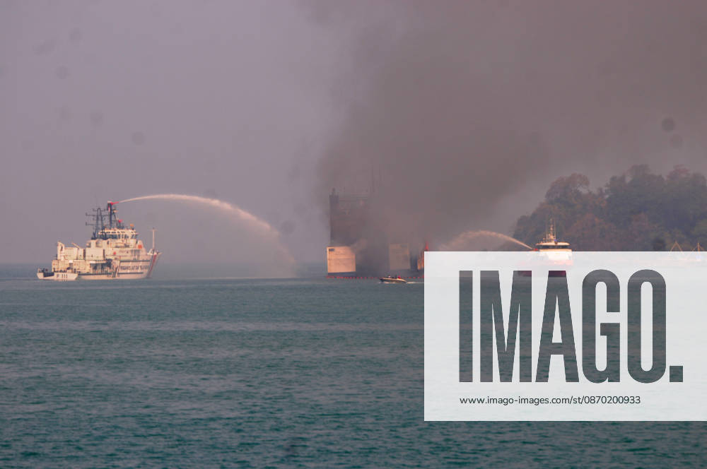 Efforts are underway to extinguish a fire that broke out on a passenger ferry in Indonesia s Cilegon PELABUHAN MERAK, CILEGON, INDONESIA - OCTOBER 21: Fireboats take turns spraying water onto the passenger ferry KMP Batumandi to cool down the vessel after it caught fire while preparing to dock off Merak Port in Cilegon, Banten, Indonesia on Wednesday, October 21, 2026. The vessel caught fire on Tuesday, October 20, and rescue operations remain underway as the ship continues to emit smoke. Water is continuously sprayed to cool the vehicle deck containing numerous cars, motorcycles, buses, and trucks, while authorities confirm no fatalities have been reported. Dasril Roszandi Anadolu Pelabuhan Merak Indonesia. Editorial use only. Please get
