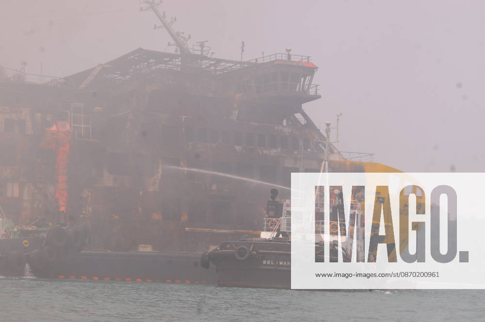 Efforts are underway to extinguish a fire that broke out on a passenger ferry in Indonesia s Cilegon PELABUHAN MERAK, CILEGON, INDONESIA - OCTOBER 21: Fireboats take turns spraying water onto the passenger ferry KMP Batumandi to cool down the vessel after it caught fire while preparing to dock off Merak Port in Cilegon, Banten, Indonesia on Wednesday, October 21, 2026. The vessel caught fire on Tuesday, October 20, and rescue operations remain underway as the ship continues to emit smoke. Water is continuously sprayed to cool the vehicle deck containing numerous cars, motorcycles, buses, and trucks, while authorities confirm no fatalities have been reported. Dasril Roszandi Anadolu Pelabuhan Merak Indonesia. Editorial use only. Please get