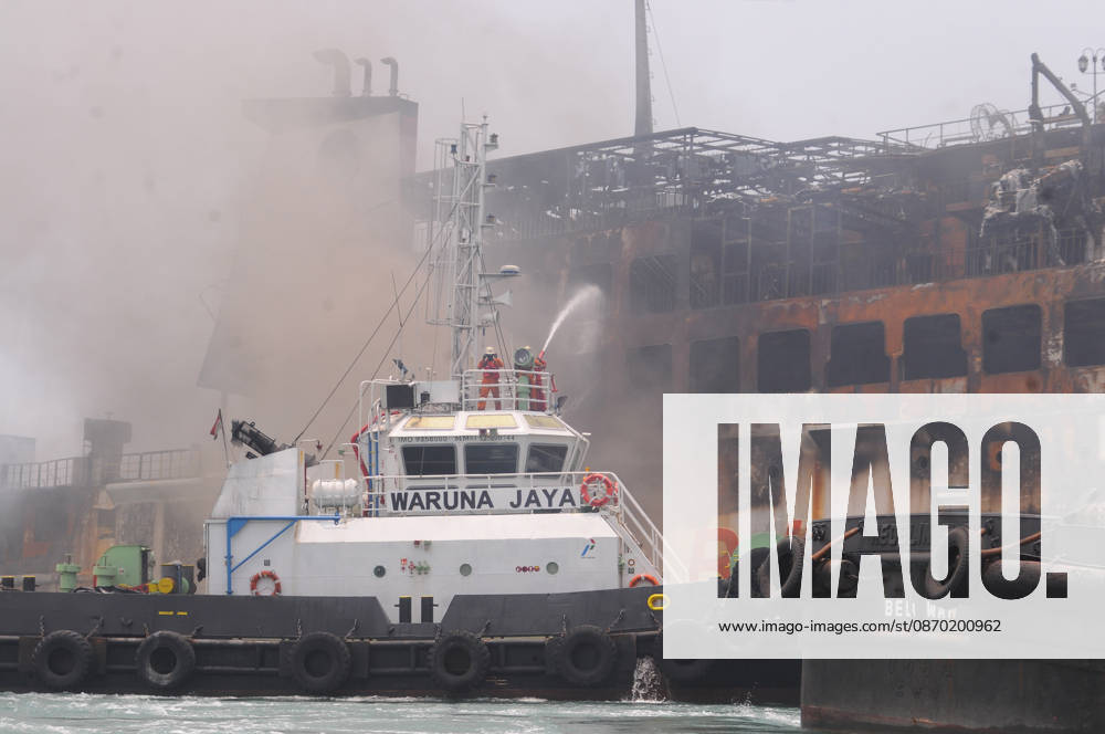 Efforts are underway to extinguish a fire that broke out on a passenger ferry in Indonesia s Cilegon PELABUHAN MERAK, CILEGON, INDONESIA - OCTOBER 21: Fireboats take turns spraying water onto the passenger ferry KMP Batumandi to cool down the vessel after it caught fire while preparing to dock off Merak Port in Cilegon, Banten, Indonesia on Wednesday, October 21, 2026. The vessel caught fire on Tuesday, October 20, and rescue operations remain underway as the ship continues to emit smoke. Water is continuously sprayed to cool the vehicle deck containing numerous cars, motorcycles, buses, and trucks, while authorities confirm no fatalities have been reported. Dasril Roszandi Anadolu Pelabuhan Merak Indonesia. Editorial use only. Please get