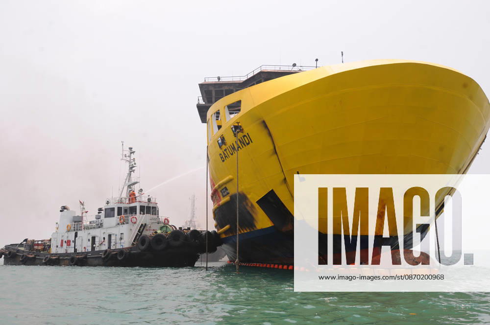 Efforts are underway to extinguish a fire that broke out on a passenger ferry in Indonesia s Cilegon PELABUHAN MERAK, CILEGON, INDONESIA - OCTOBER 21: Fireboats take turns spraying water onto the passenger ferry KMP Batumandi to cool down the vessel after it caught fire while preparing to dock off Merak Port in Cilegon, Banten, Indonesia on Wednesday, October 21, 2026. The vessel caught fire on Tuesday, October 20, and rescue operations remain underway as the ship continues to emit smoke. Water is continuously sprayed to cool the vehicle deck containing numerous cars, motorcycles, buses, and trucks, while authorities confirm no fatalities have been reported. Dasril Roszandi Anadolu Pelabuhan Merak Indonesia. Editorial use only. Please get