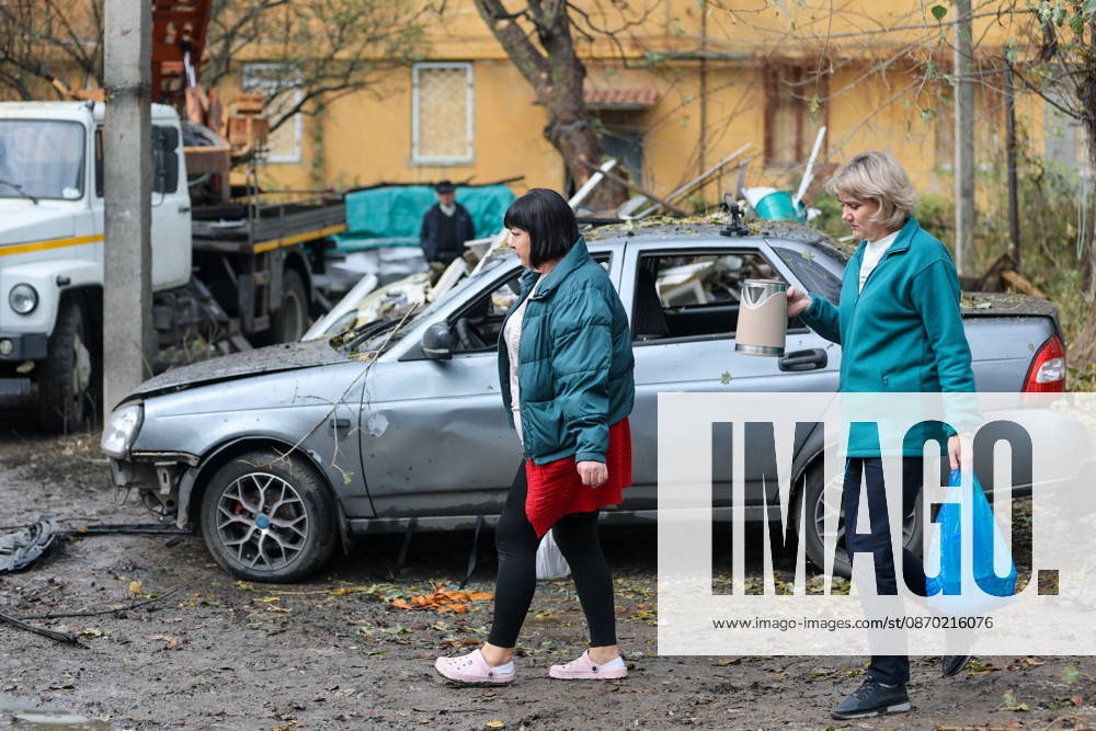 RUSSIA, DONETSK - OCTOBER 21, 2026: Women walk past a car damaged by a Ukrainian drone strike on Proletarsky District. Dmitry Yagodkin TASS 99703677