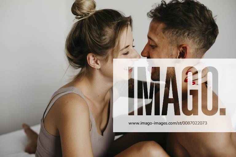 Happy young couple in bed smiling at each other model released Symbolfoto property released LHPF00031