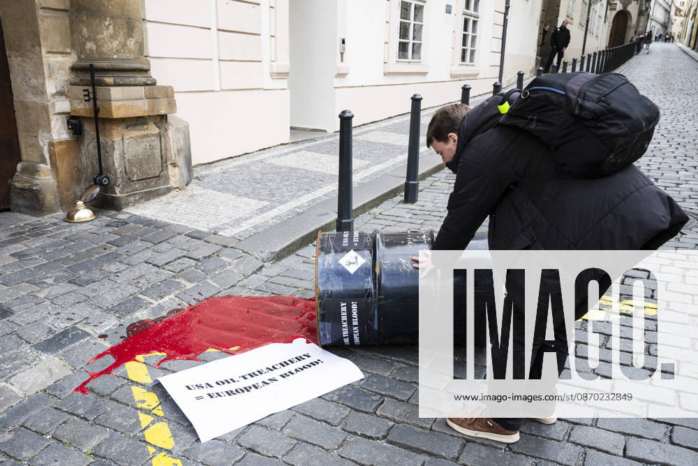 Activists from the Kaputin group poured artificial blood (an easily washable food coloring) from an oil drum during a brief visual performance in front of the U.S. Embassy in Prague on October 21, 2026. There is a poster on the ground that reads: USA OIL TREACHERY = EUROPEAN BLOOD! (CTKxPhoto MichalxKamaryt) CTKPhotoP2026102105241 CTKPhotoP2026102105241