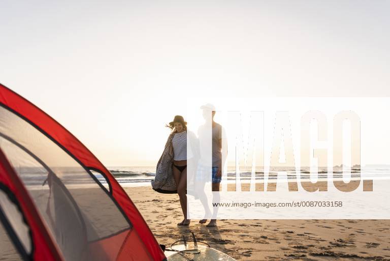 Romantic couple camping on the beach, doing a beach stroll at sunset model released Symbolfoto UUF15151