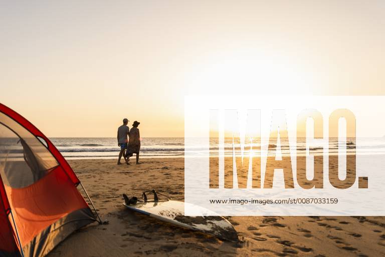 Romantic couple camping on the beach, doing a beach stroll at sunset model released Symbolfoto UUF15154