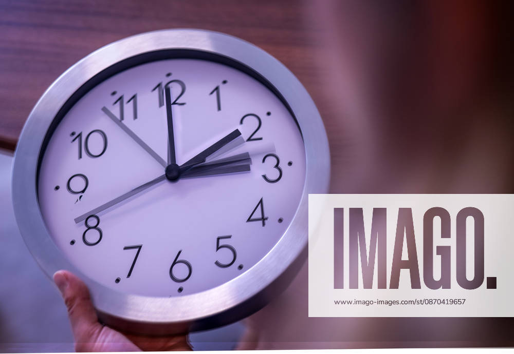 Time change from summer to winter: Setting the time on an analog wall clock with hands from 3:00 to 2:00 (winter time)